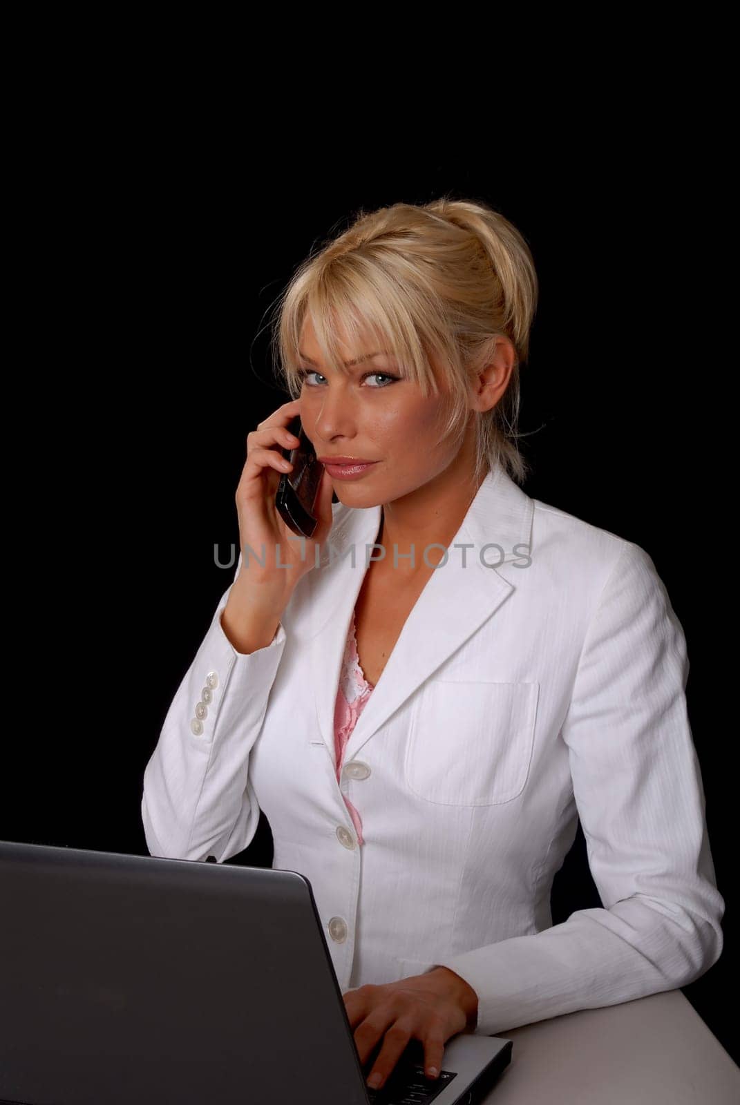 Lovely blond business woman working at laptop computer on cell phone