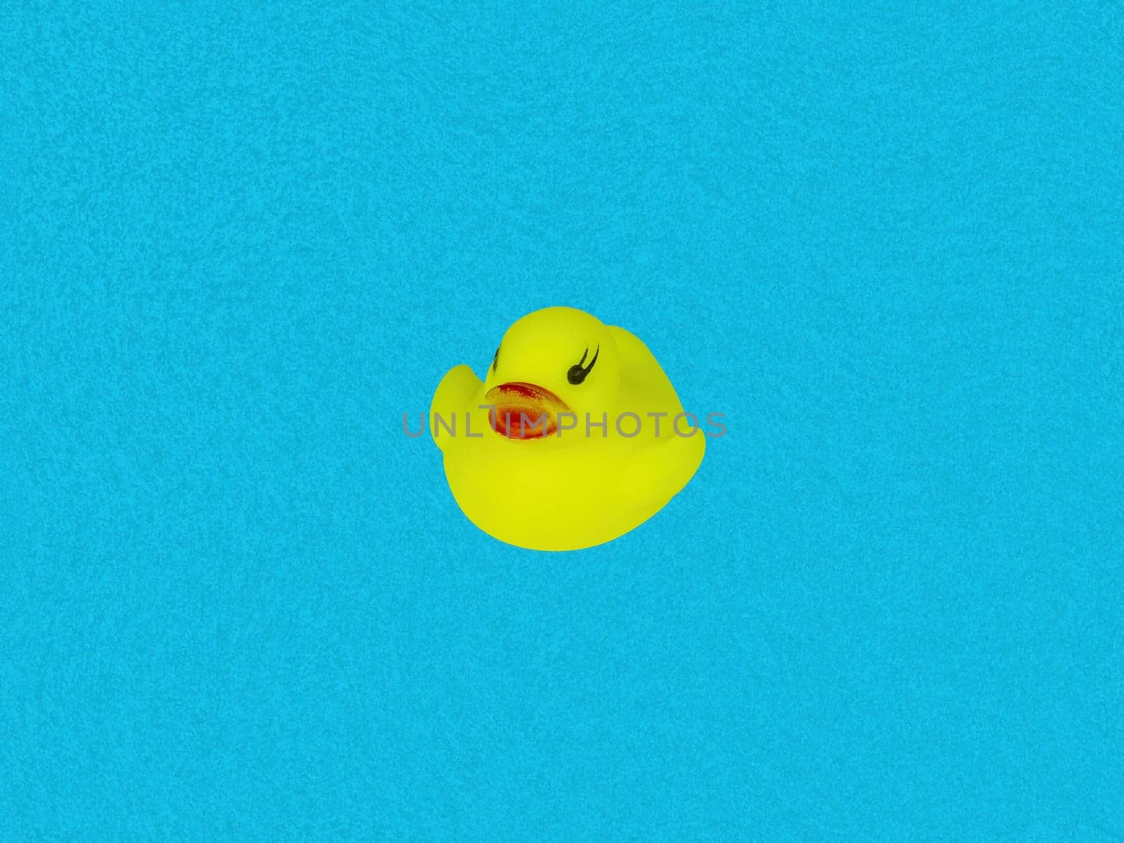 Children's toy bird yellow duckling on a blue background of water. Duck bird. Kids toys. Blue water color background. Little ducklings. An object of entertainment for kids.