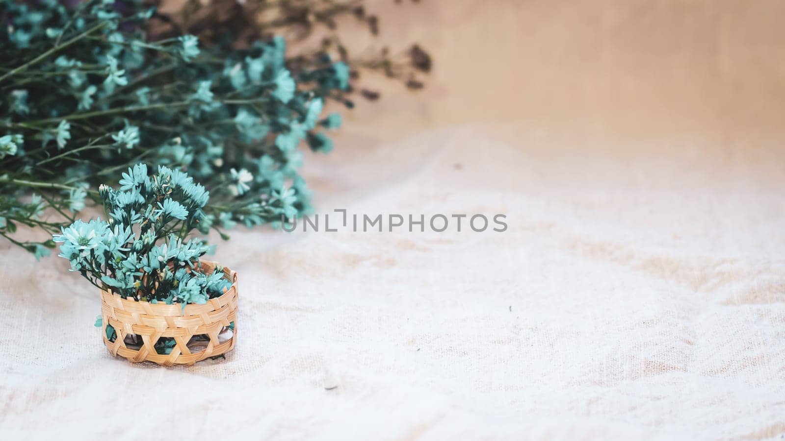 Macro small white flowers in a small bamboo woven basket on a linen fabric background