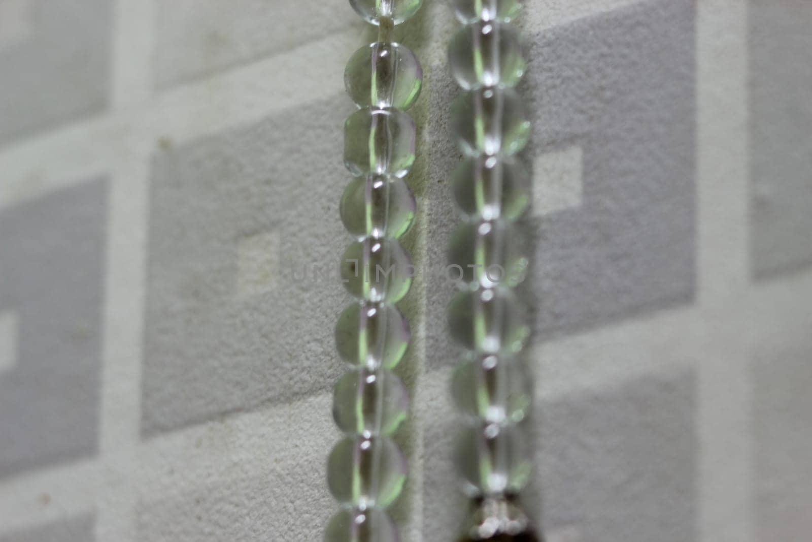 Macro photograph with selective focus of glass shiny prayer beads or rosary with copy space for text. Religion concept of ramadan or Eid for muslims.