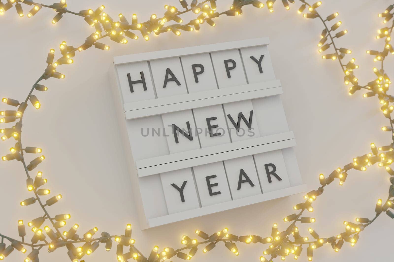 3d illustration. Happy New Year Text Light Box and Glowing light bulbs Christmas and New Year on white background . Copy Space For Message.