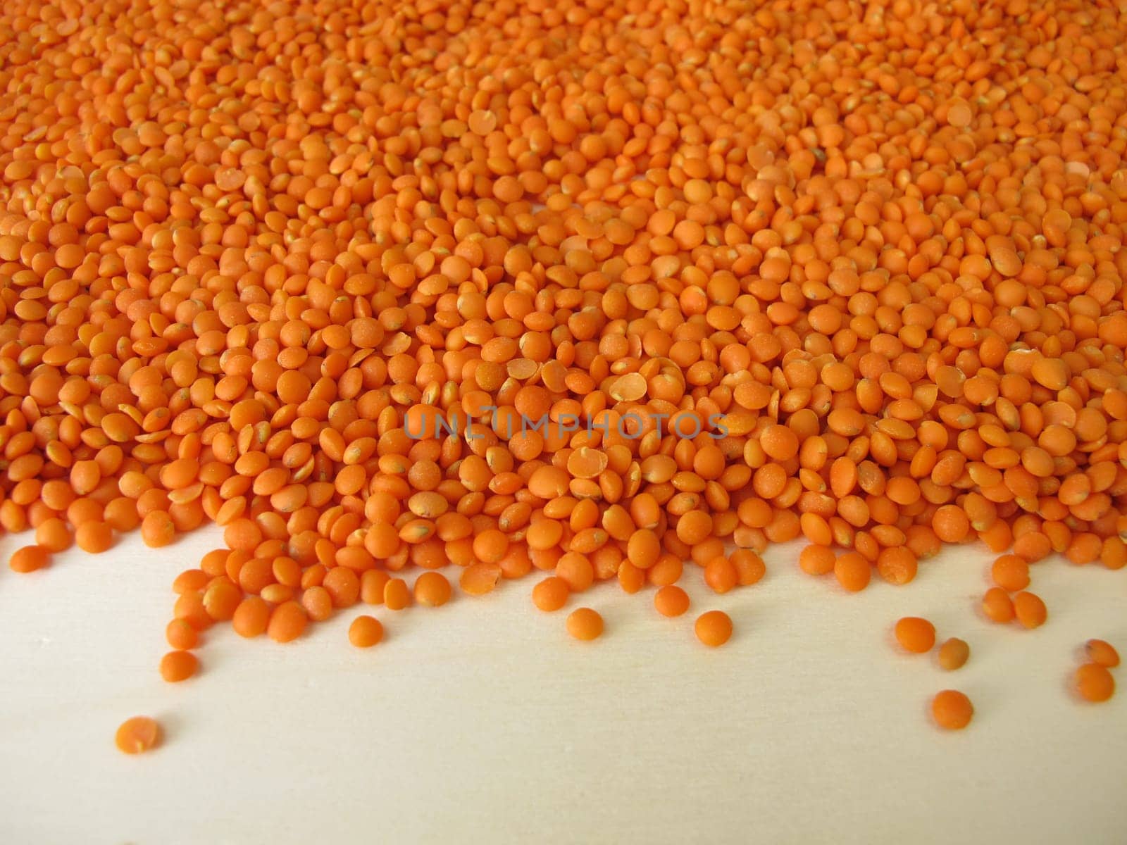Red lentils distributed flatly on a wooden board
