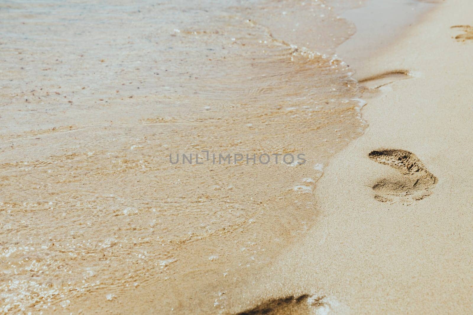 Footprint, step imprint at sand. Sea and soft ocean waves on golden sandy tropical island summer beach, holidays border frame concept background, vacation backdrop, copy space. Walk through coastline