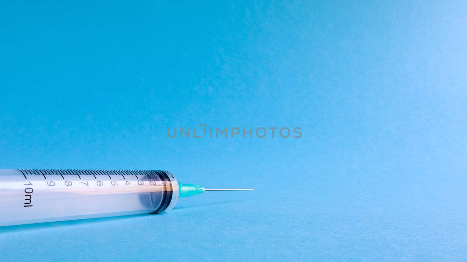 On a blue background lies a medical syringe with a needle. epidemic. Copy space The concept of collecting blood and injection vaccines, medical equipment for hypodermic injection, healthcare theme