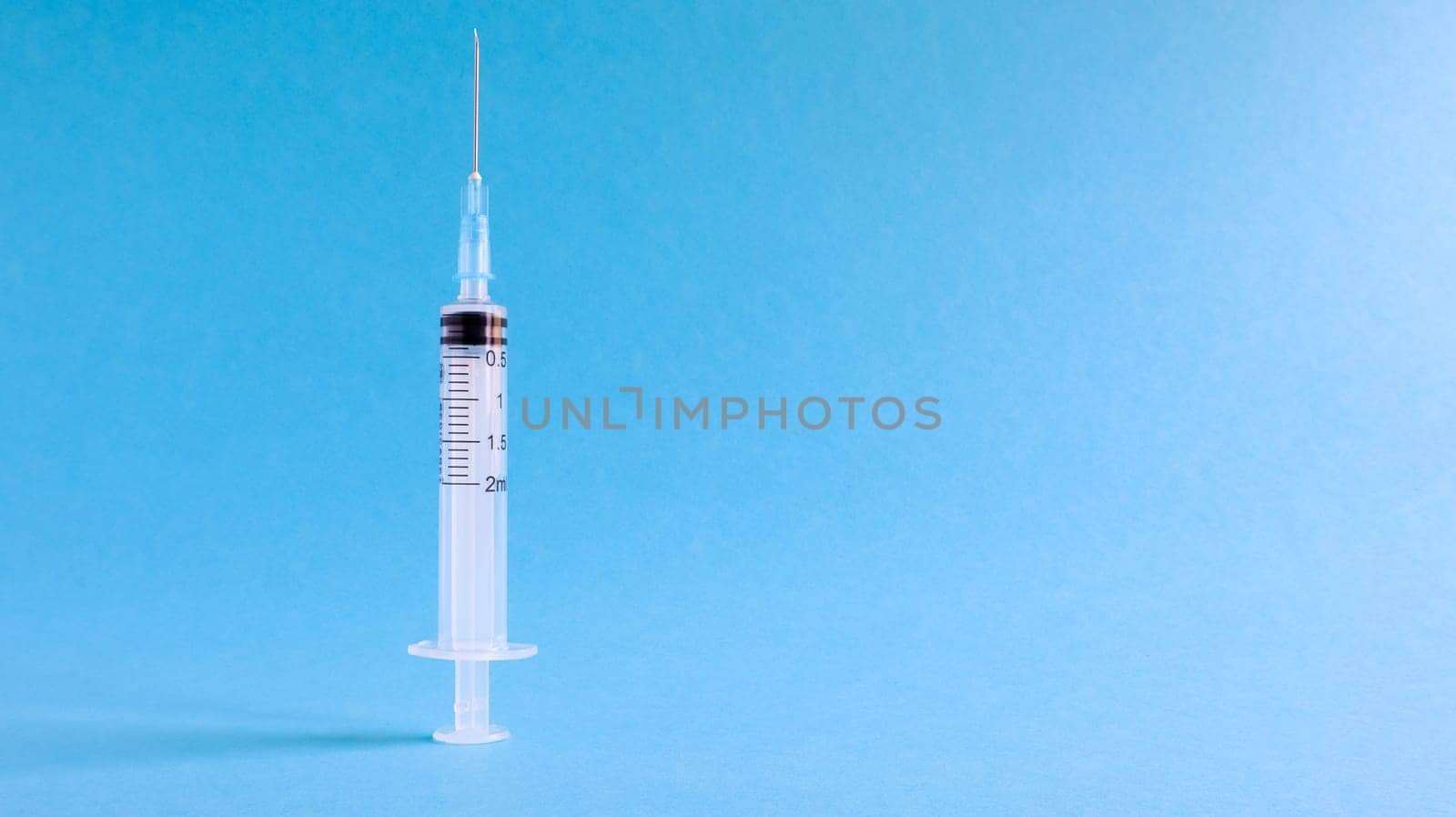 On a blue background lies a medical syringe with a needle. epidemic. Copy space The concept of collecting blood and injection vaccines, medical equipment for hypodermic injection, healthcare theme