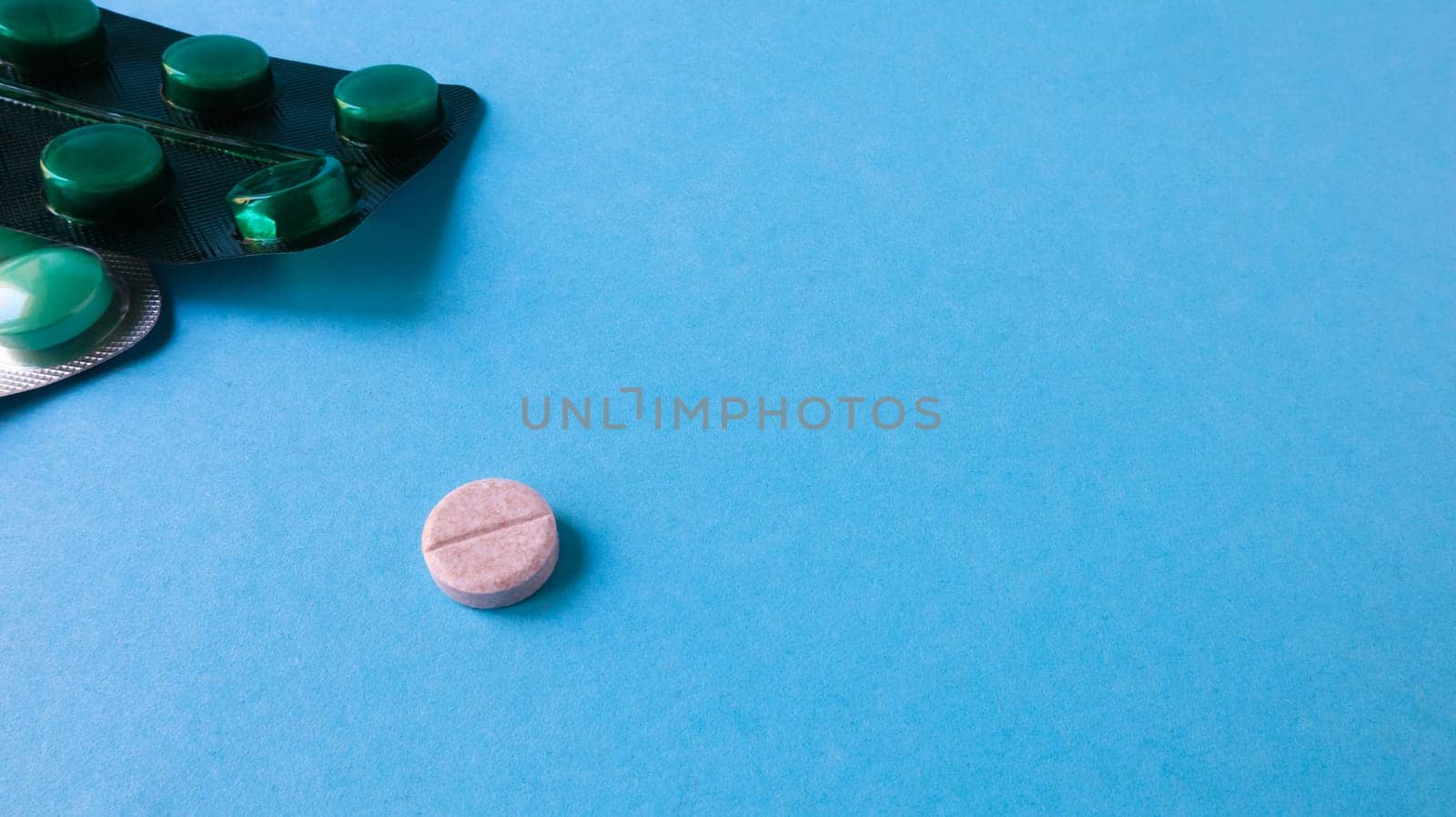 Two packs of pills and one round pill to the side on a blue background with copy space. antiviral tablets for pneumonia and bacterial infection. medicines and wellness treatments