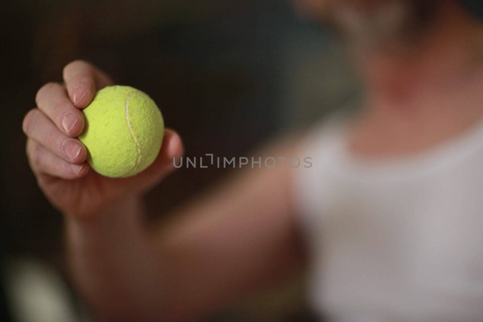 yellow tennis ball in tennis player's hand soft focus