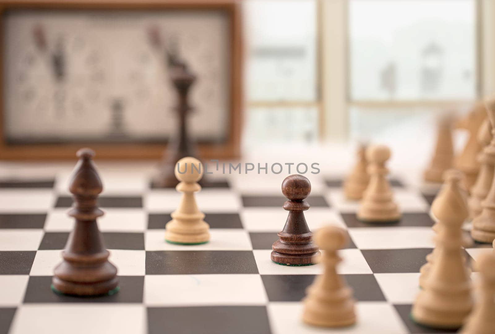 The chess board with clock and figures in front of a blurry window