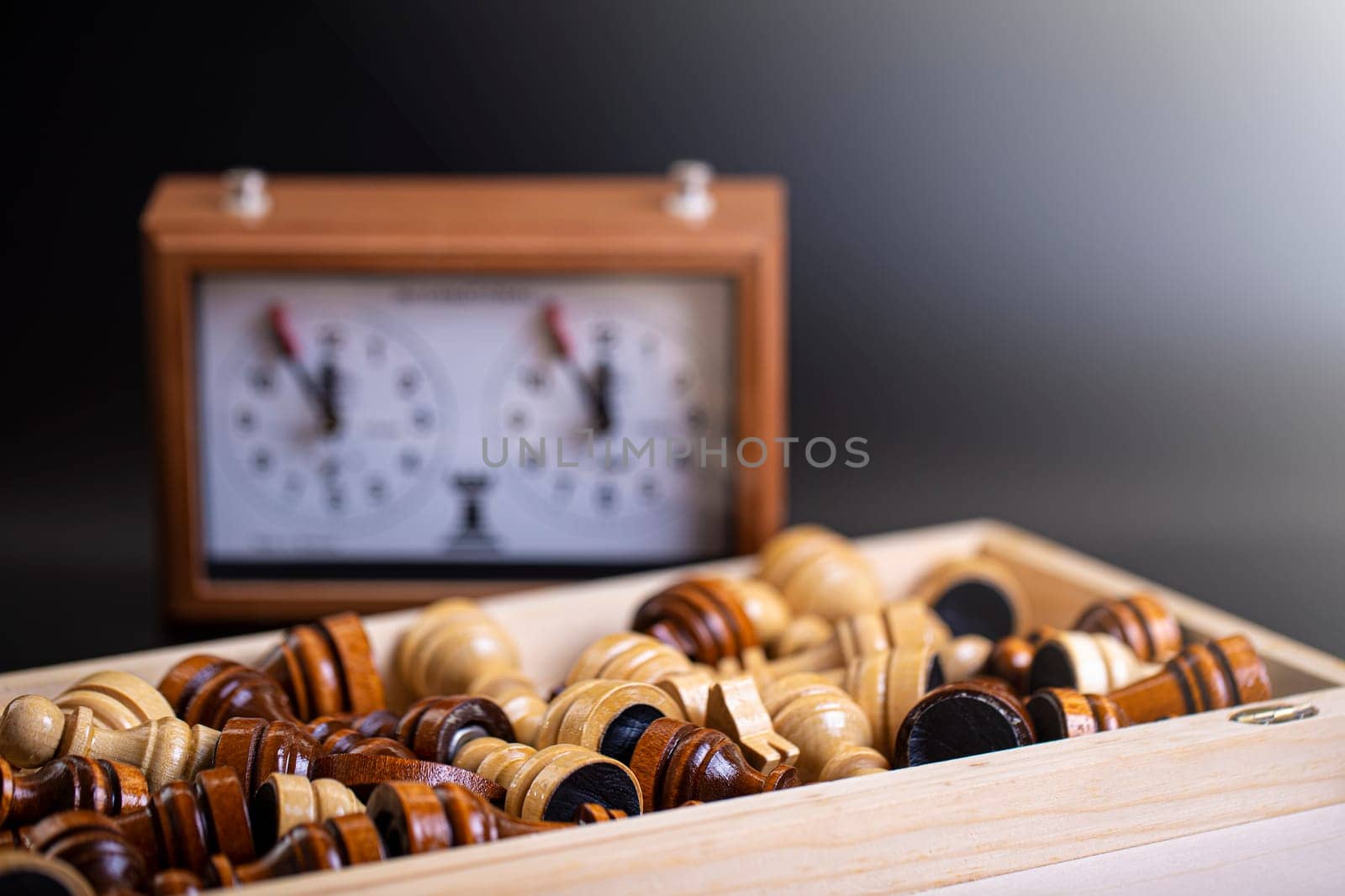 The Chess pieces on a board and a chess clock on a dark background
