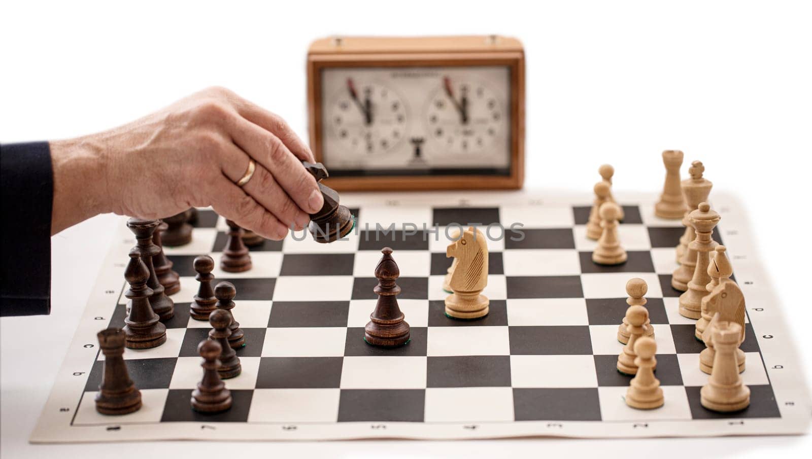 The chess board with clock and figures on white background, selective focus