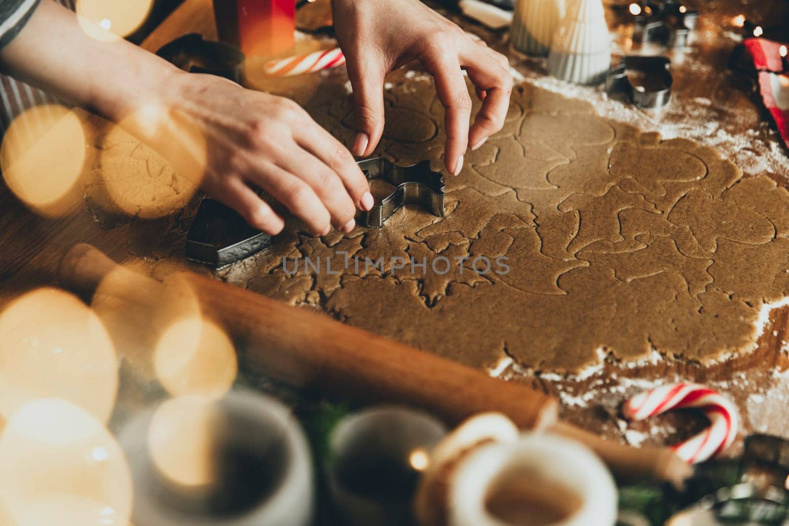 Merry Christmas, Happy New Year. Gingerbread cookies cooking, baking. Young woman sculpts, cuts and carves gingerbread cookie figures from kneaded dough using special kitchen forms. High quality photo