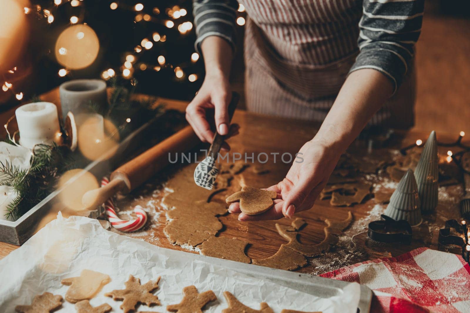 Merry Christmas, Happy New Year. Gingerbread cookies cooking, baking. Young woman sculpts, cuts and carves gingerbread cookie figures from kneaded dough using special kitchen forms. High quality photo