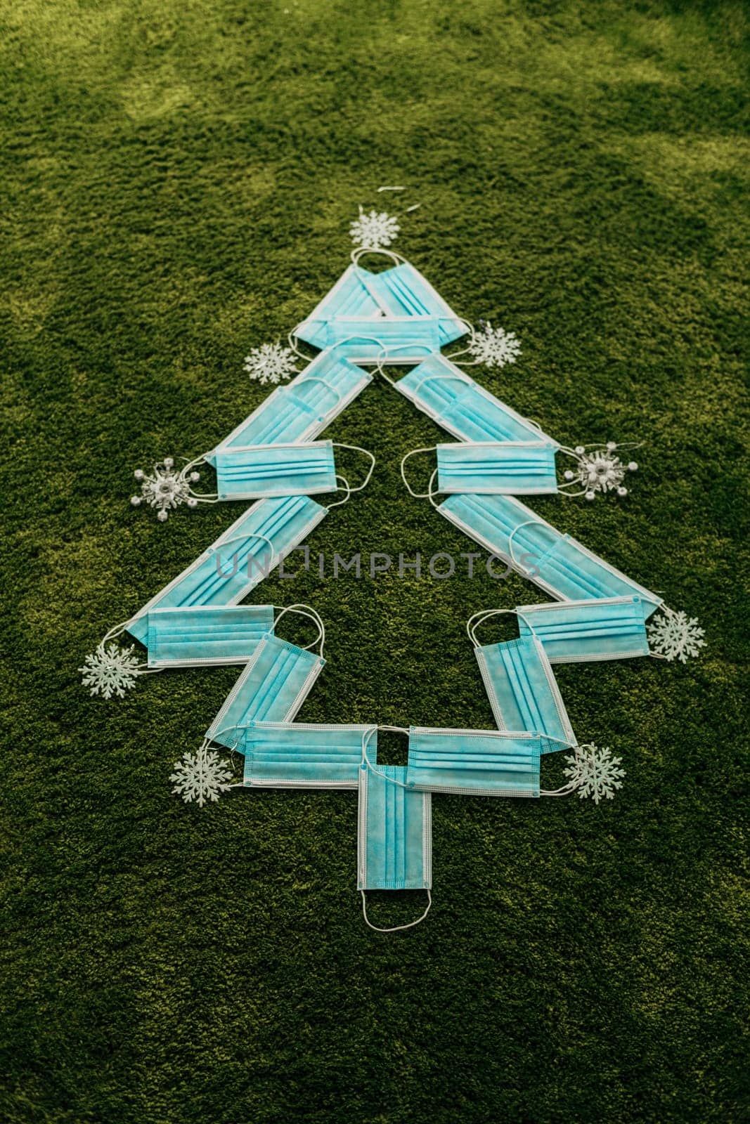 Christmas Tree Made of Blue Medical Masks on a Green Background
