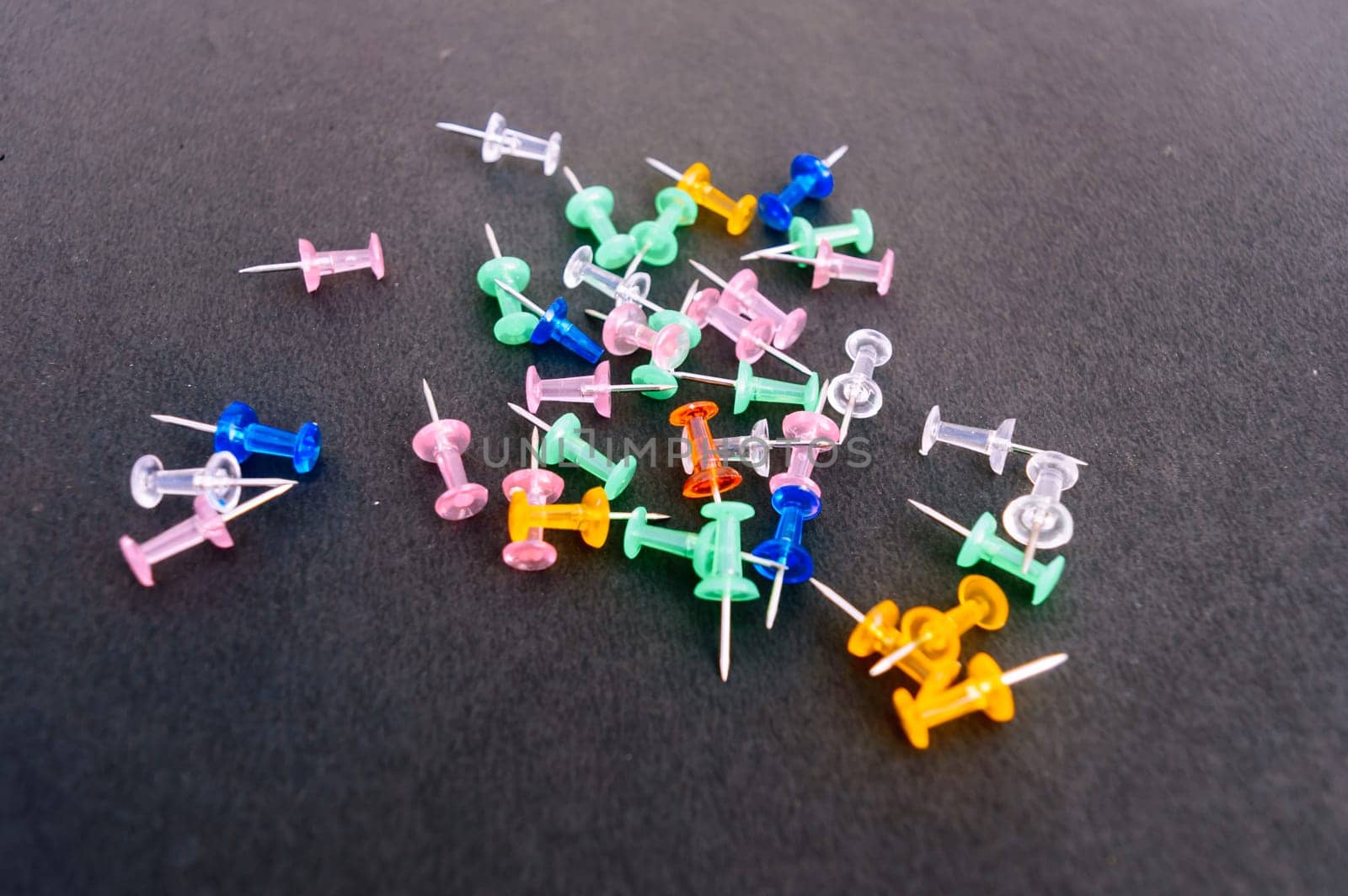 Notice Board Pin placed on a table isolated on black background. High angle view.