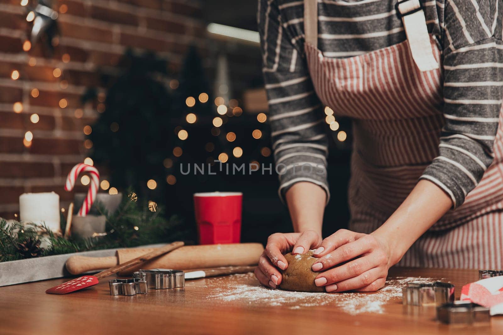 Merry Christmas, Happy New Year. Gingerbread cooking, cake, biscuit or strudel baking. Woman in apron is kneading dough. Girl gently holding, creases, cook and bake. Christmas decorations at kitchen