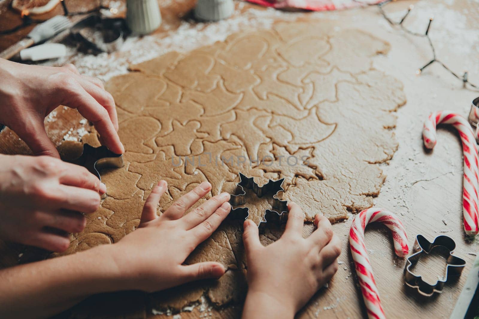 Merry Christmas, Happy New Year. Gingerbread cooking, baking. Mom and daughter make cookies, cut out different shapes of cookies using cutting metal mold on wooden table at kitchen. High quality photo