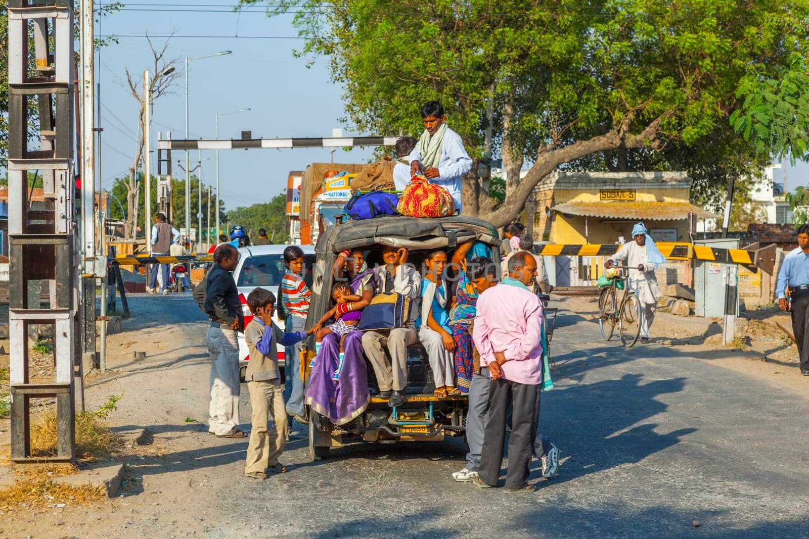 Fatehpur Sikri, India -  November 16, 2011: people wait at the railway crossing near Fatehpur Sikri, India. Cars are overloaded with people and goods.