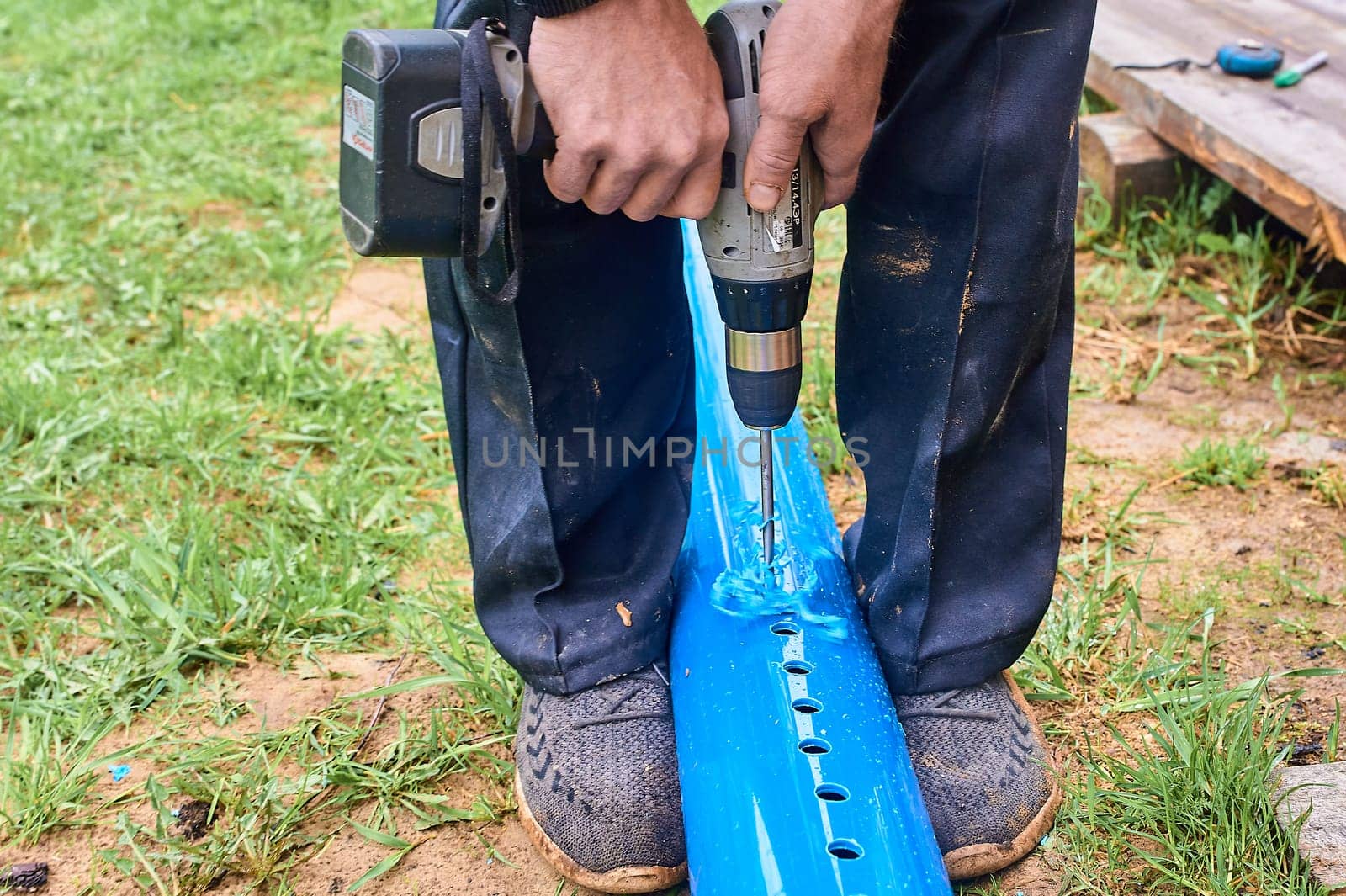drill holes in the plastic blue pipe with a screwdriver outdoors. High quality photo