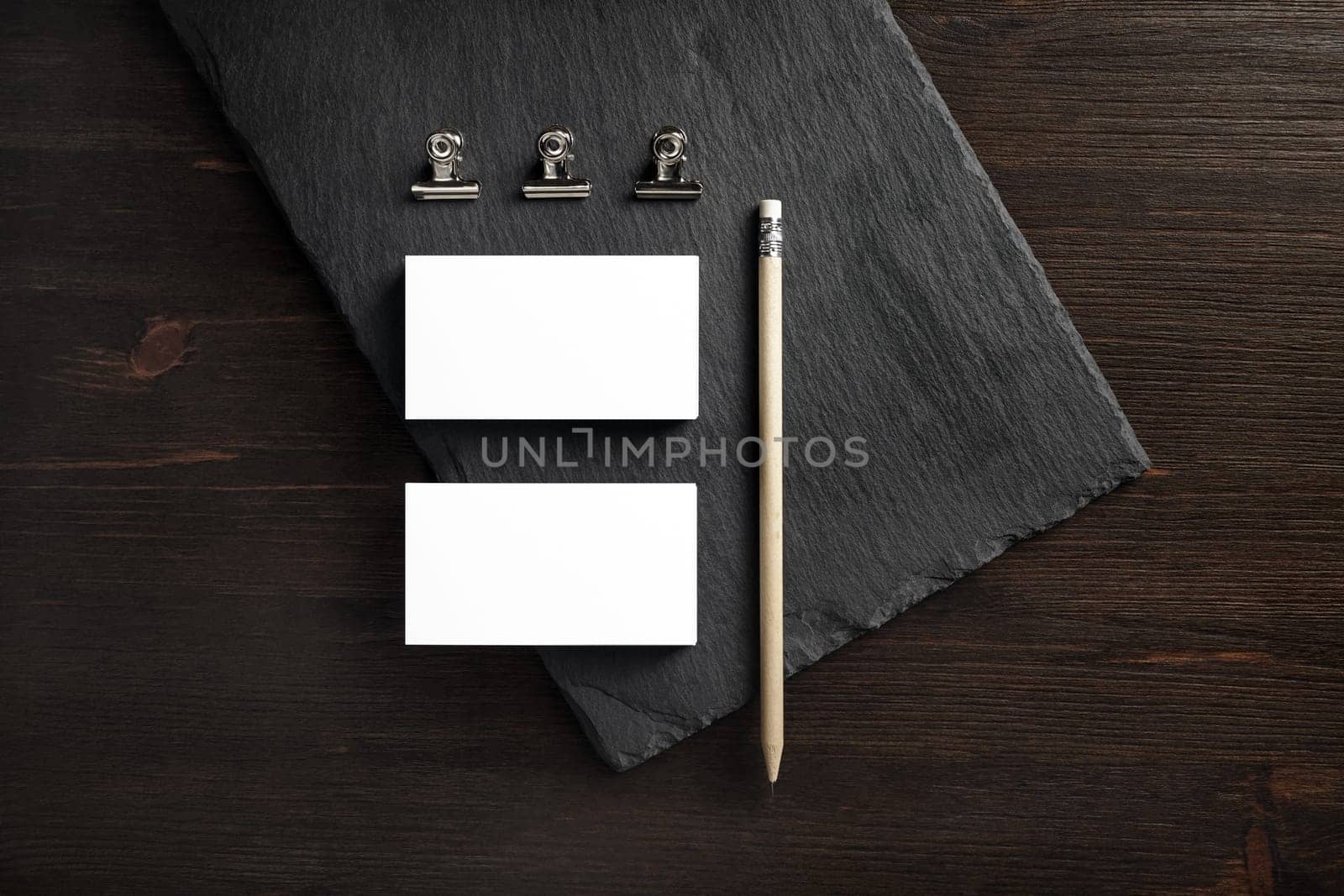 Blank business cards, pencil and clips on stone board. Flat lay.