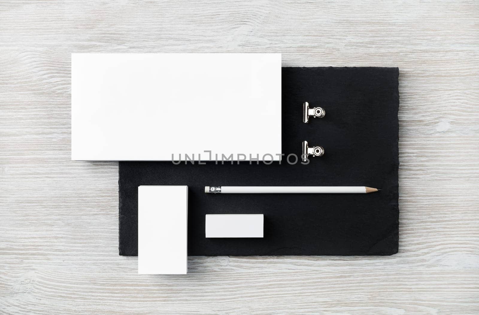 Blank stationery set. Envelope, business card, pencil, eraser and clips on stone board. Flat lay.