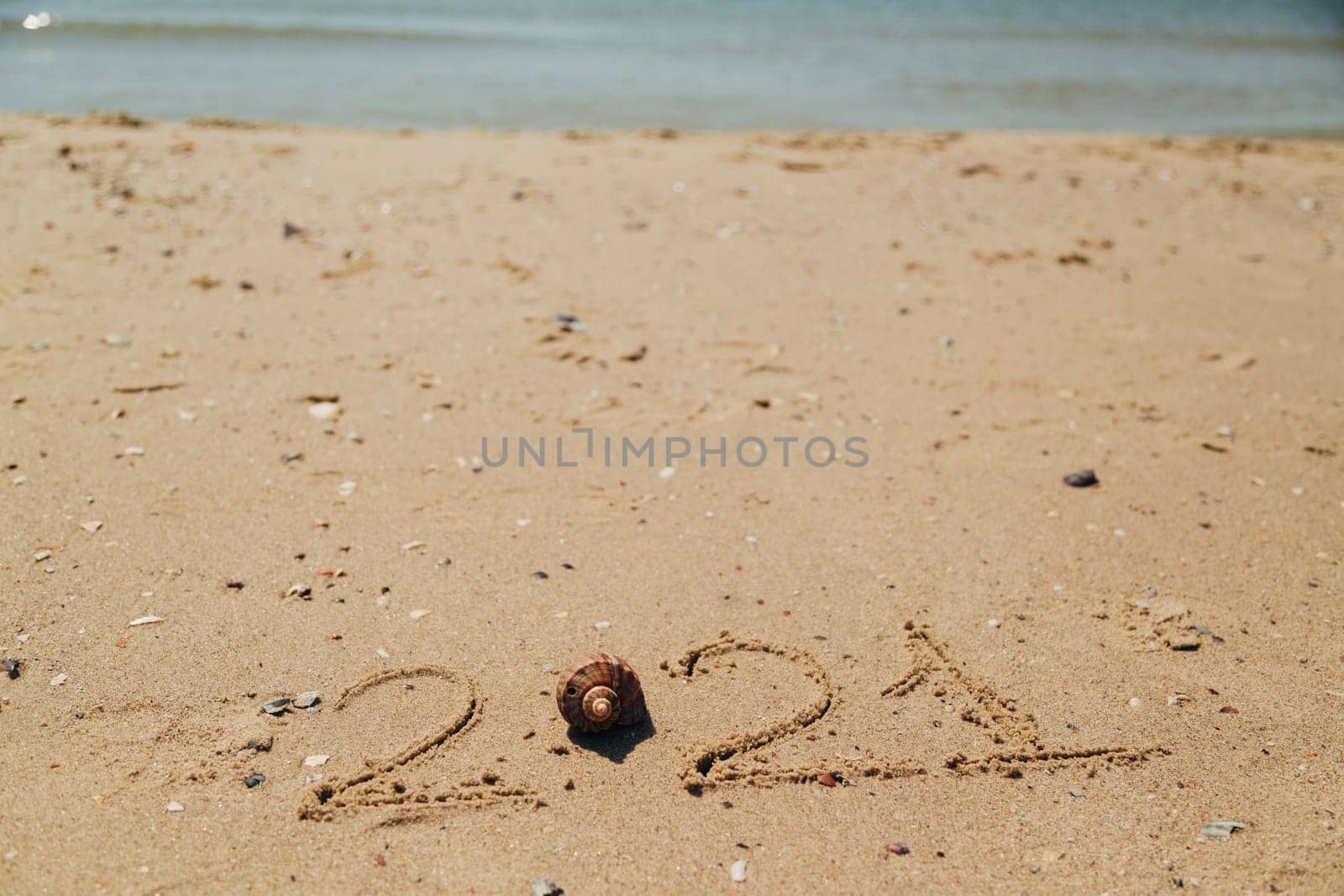 Text 2021 Written on the Sand of a Beach. Sea on a Background of Letters