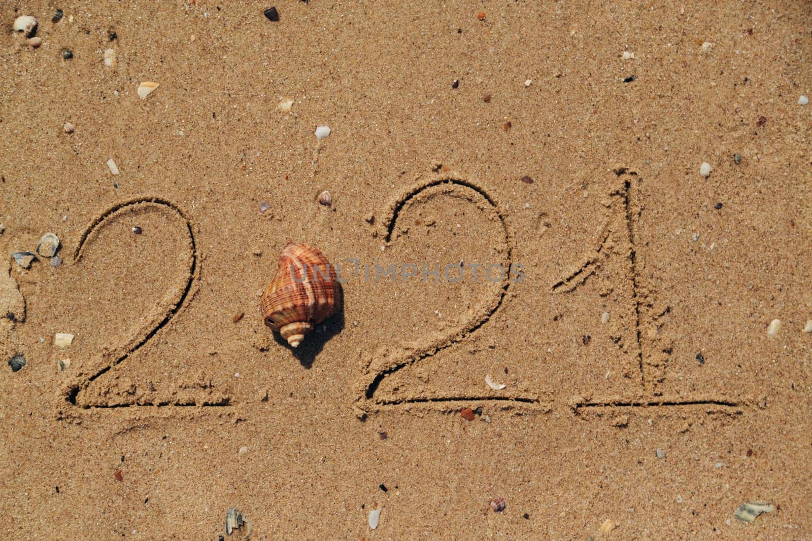 Word 2021 Written on the Sand of a Beach. New Year 2021 text on the sea beach. Vacation relax