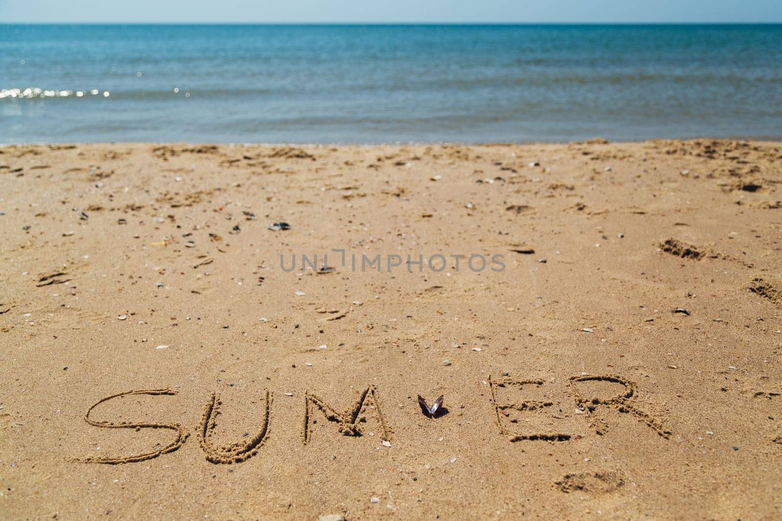 Text Summer Written on the Sand of a Beach. Sea on a Background of Letters