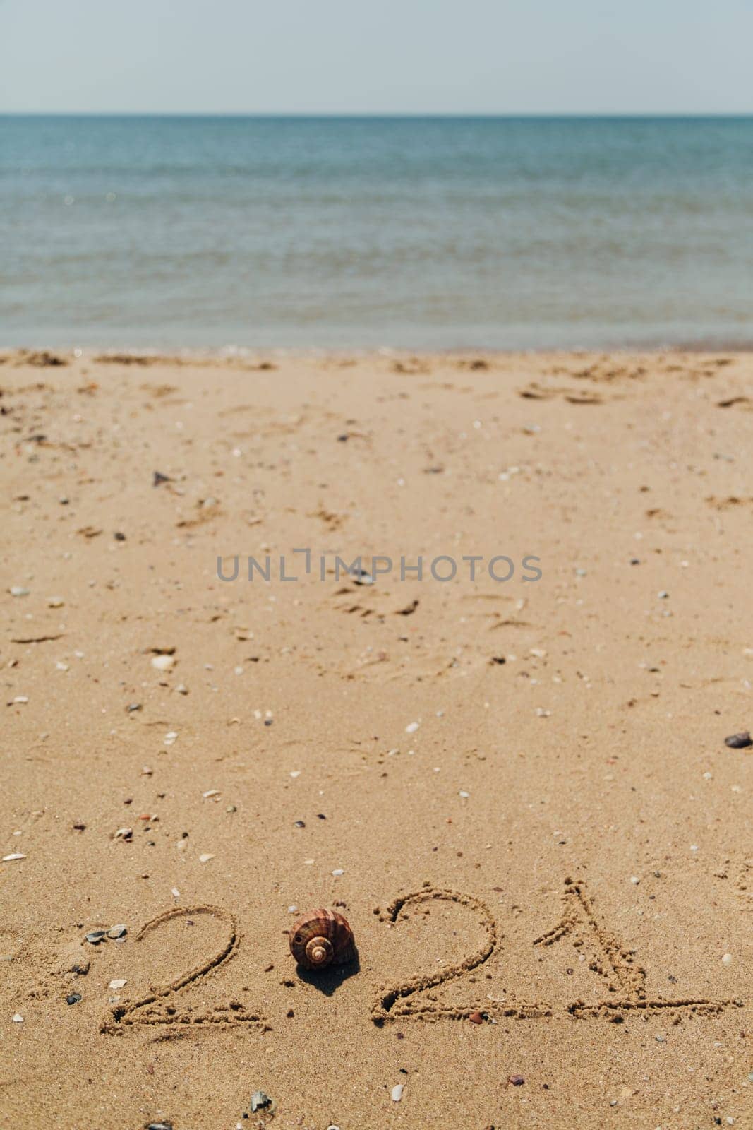 Text 2021 Written on the Sand of a Beach. Sea on a Background of Letters