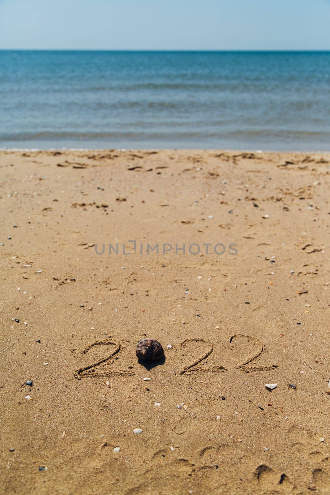 Text 2022 Written on the Sand of a Beach. Sea on a Background of Letters