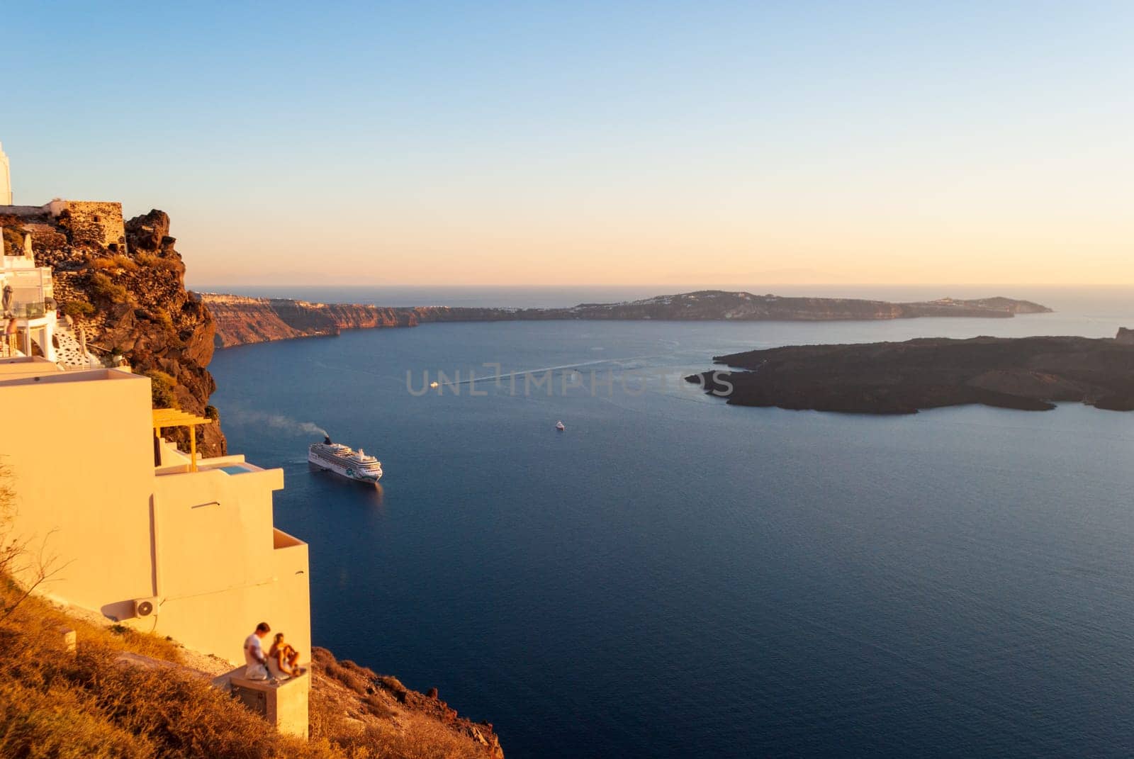 View of the bay of Santorini and the cruise ship during sunset.