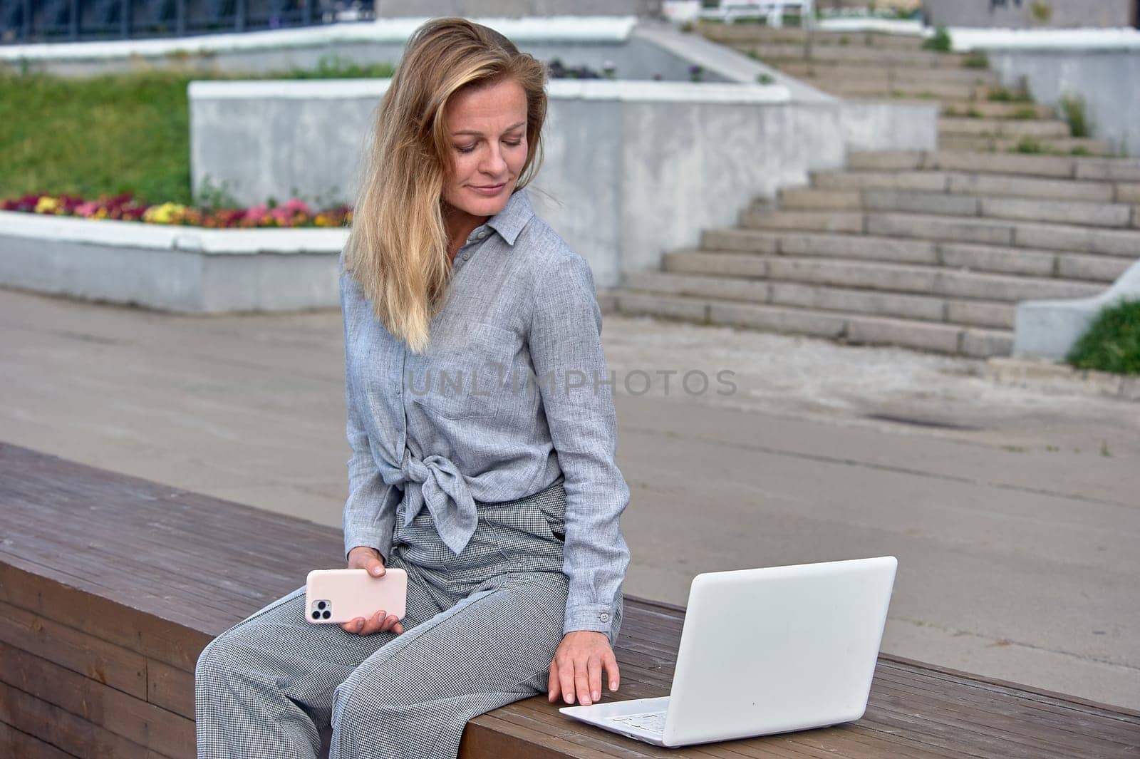 A woman with a laptop sits on a wooden platform, works online. High quality photo