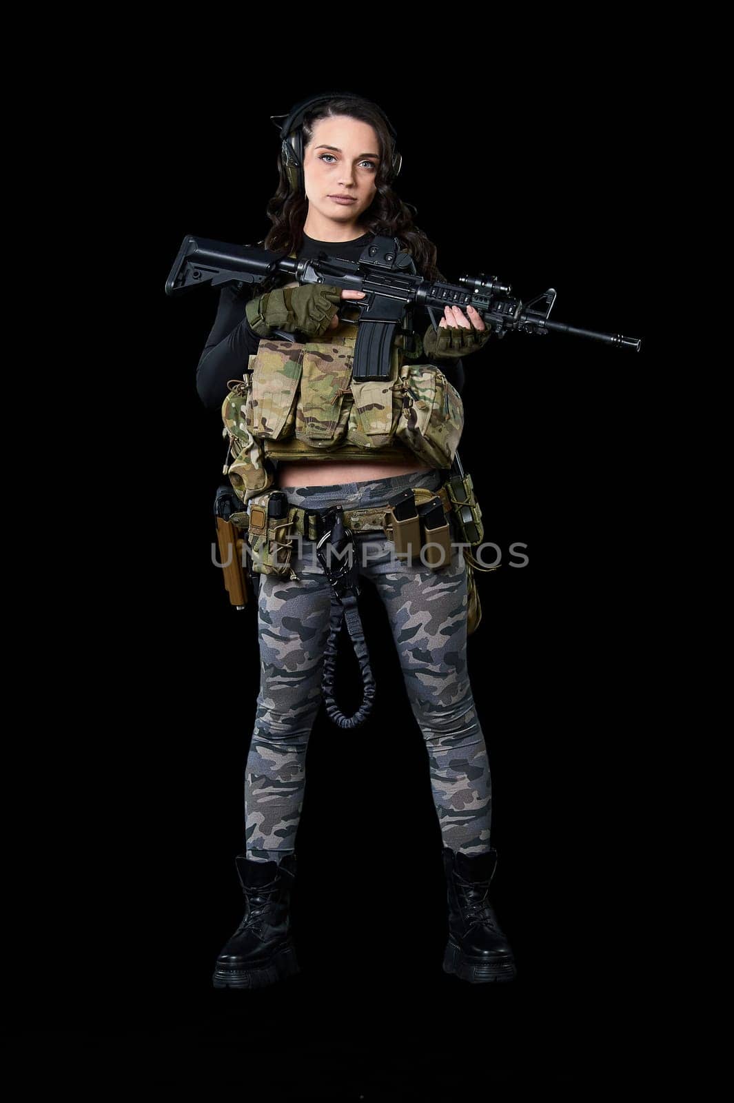 Young woman stands with a rifle on a black background. High quality photo