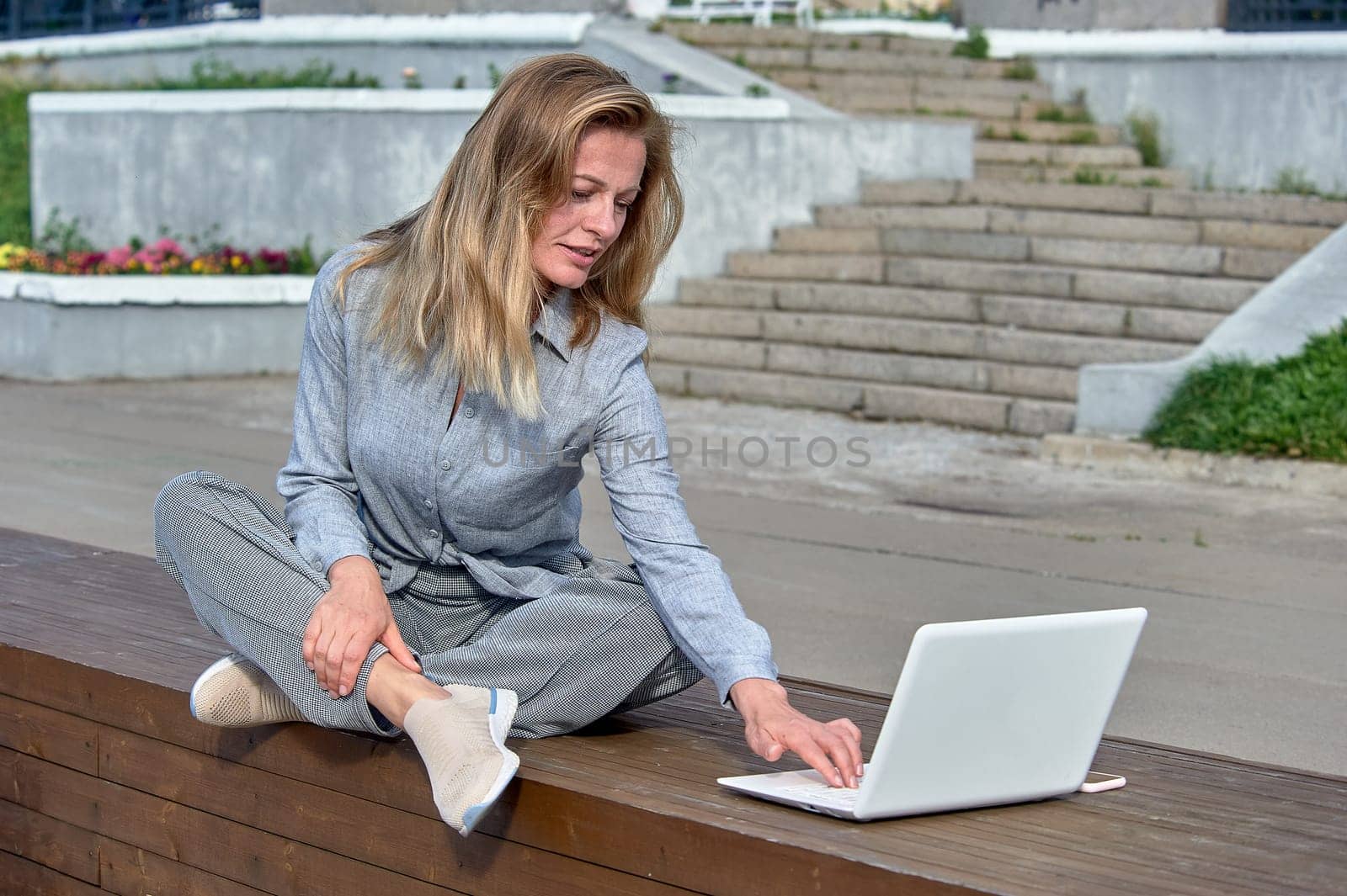 A woman with a laptop sits on a wooden platform, works online. High quality photo