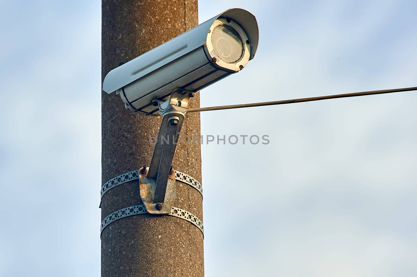 A security camera is hanging on a concrete post. High quality photo
