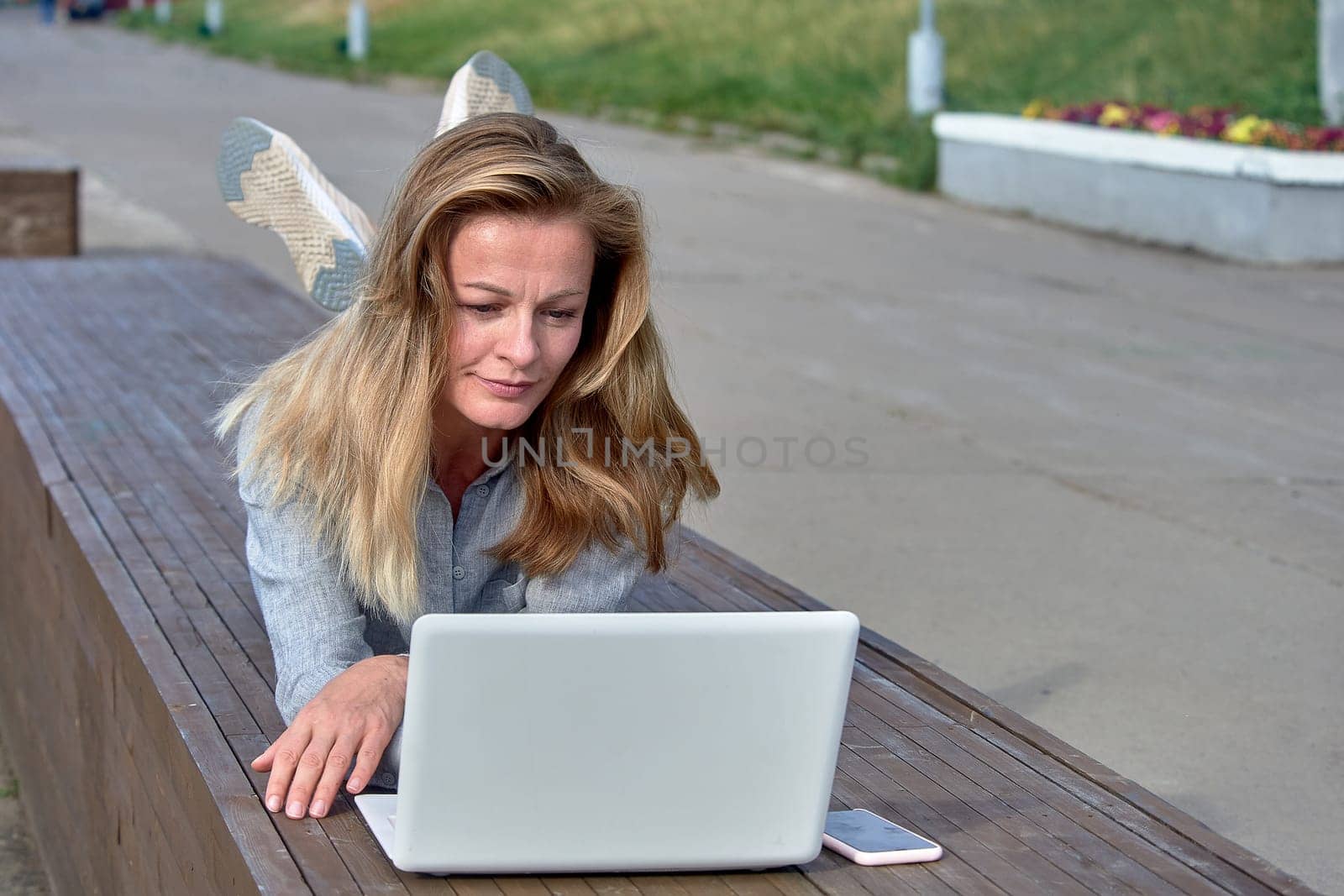 A woman with a laptop sits on a wooden platform, works online. High quality photo