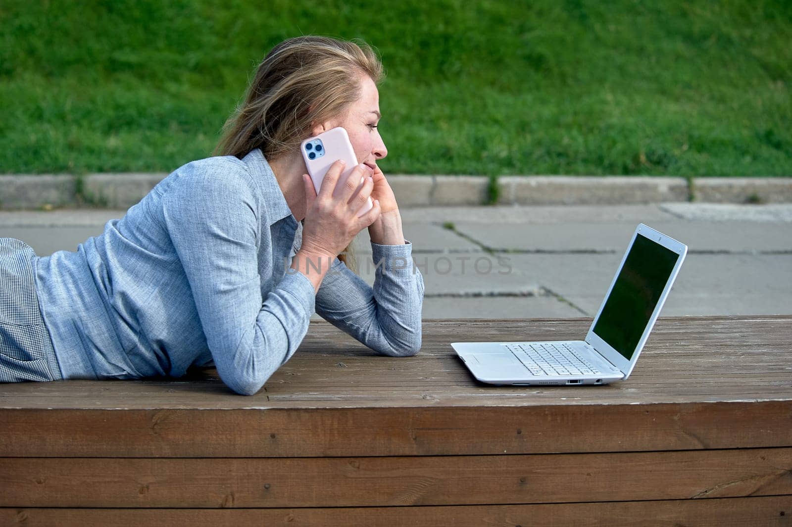 A woman with a laptop sits on a wooden platform, works online. High quality photo