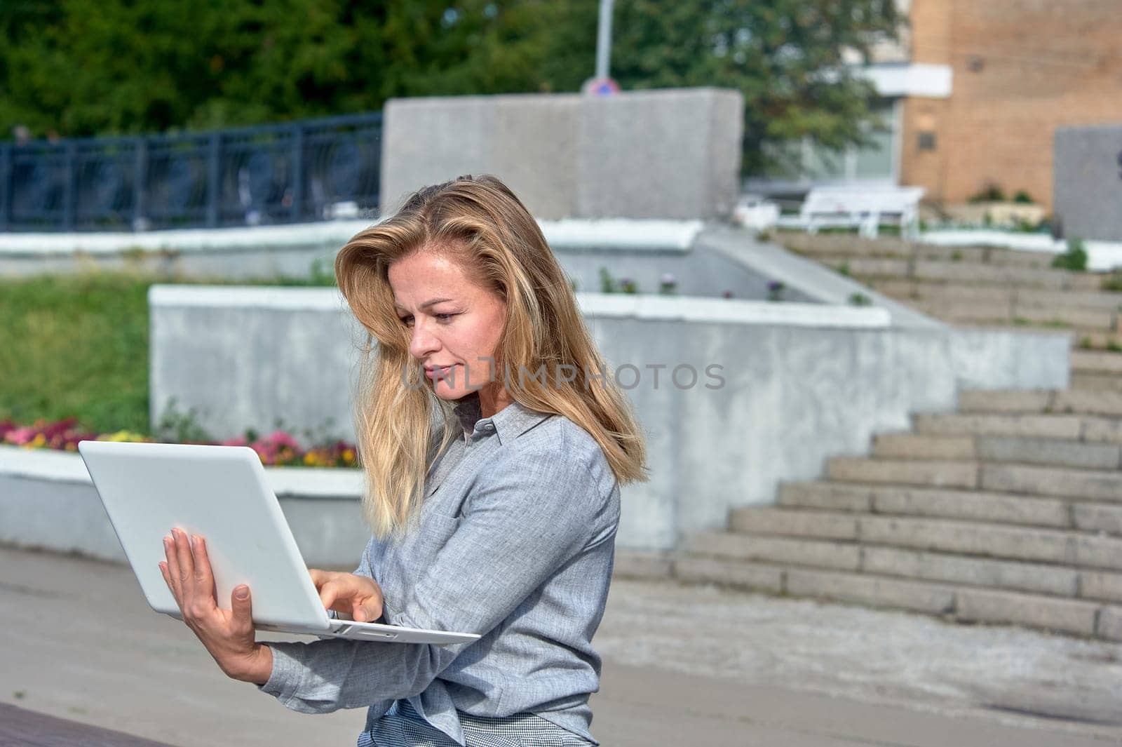 A woman with a laptop sits on a wooden platform, works online. High quality photo