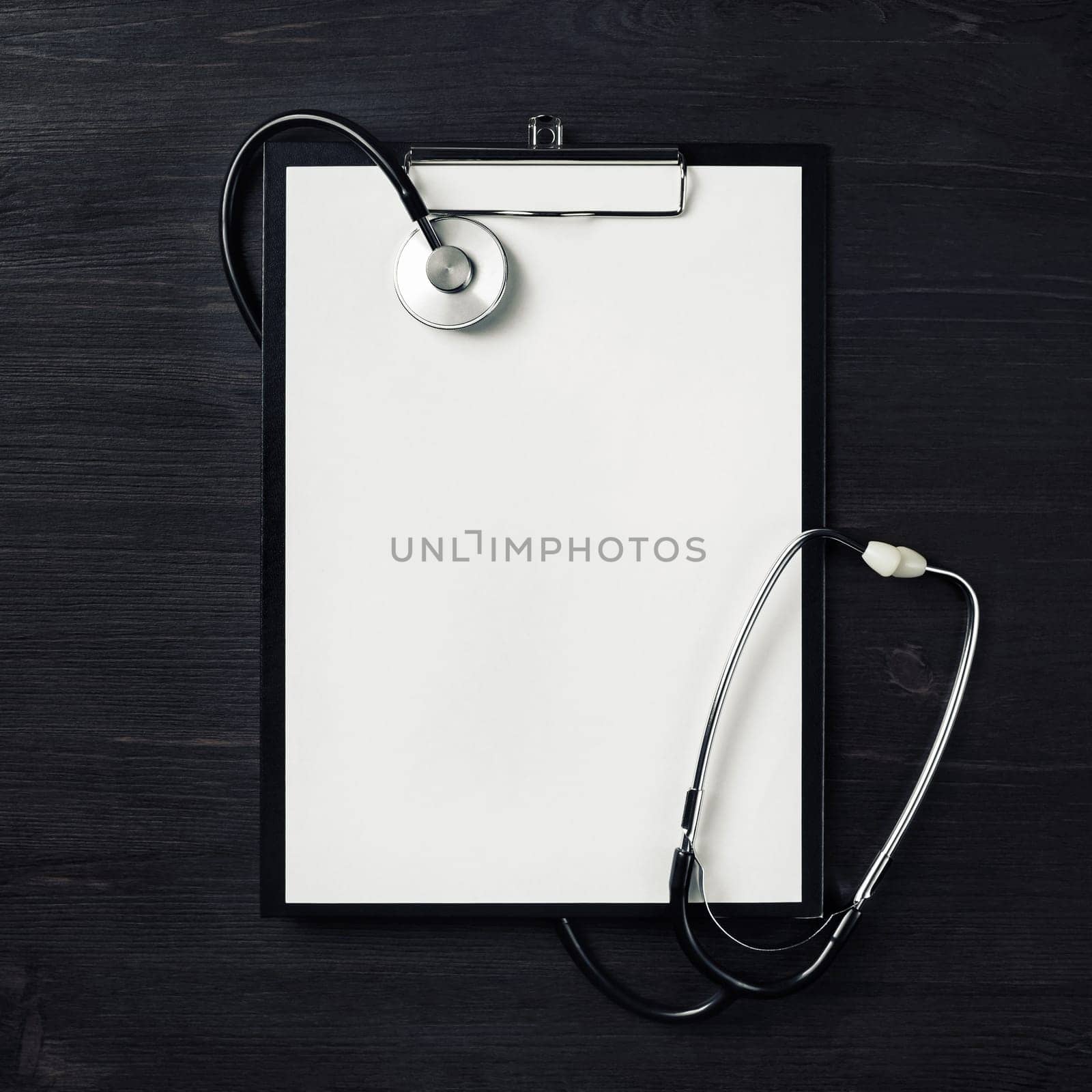 Blank clipboard with stethoscope on wood table background. Top view. Flat lay.
