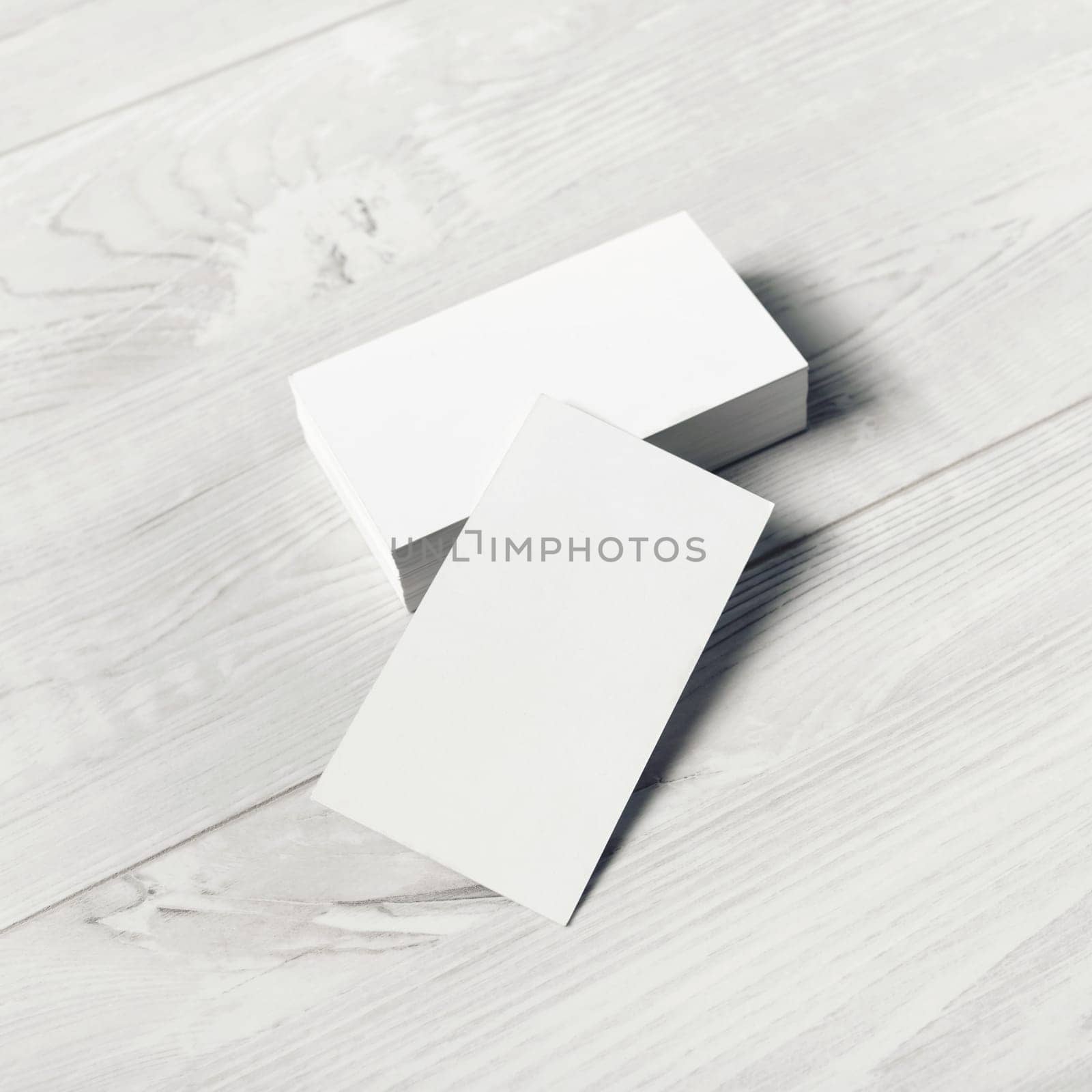 Blank white business cards on light wooden background. Mockup for ID. Template for graphic designers portfolios.
