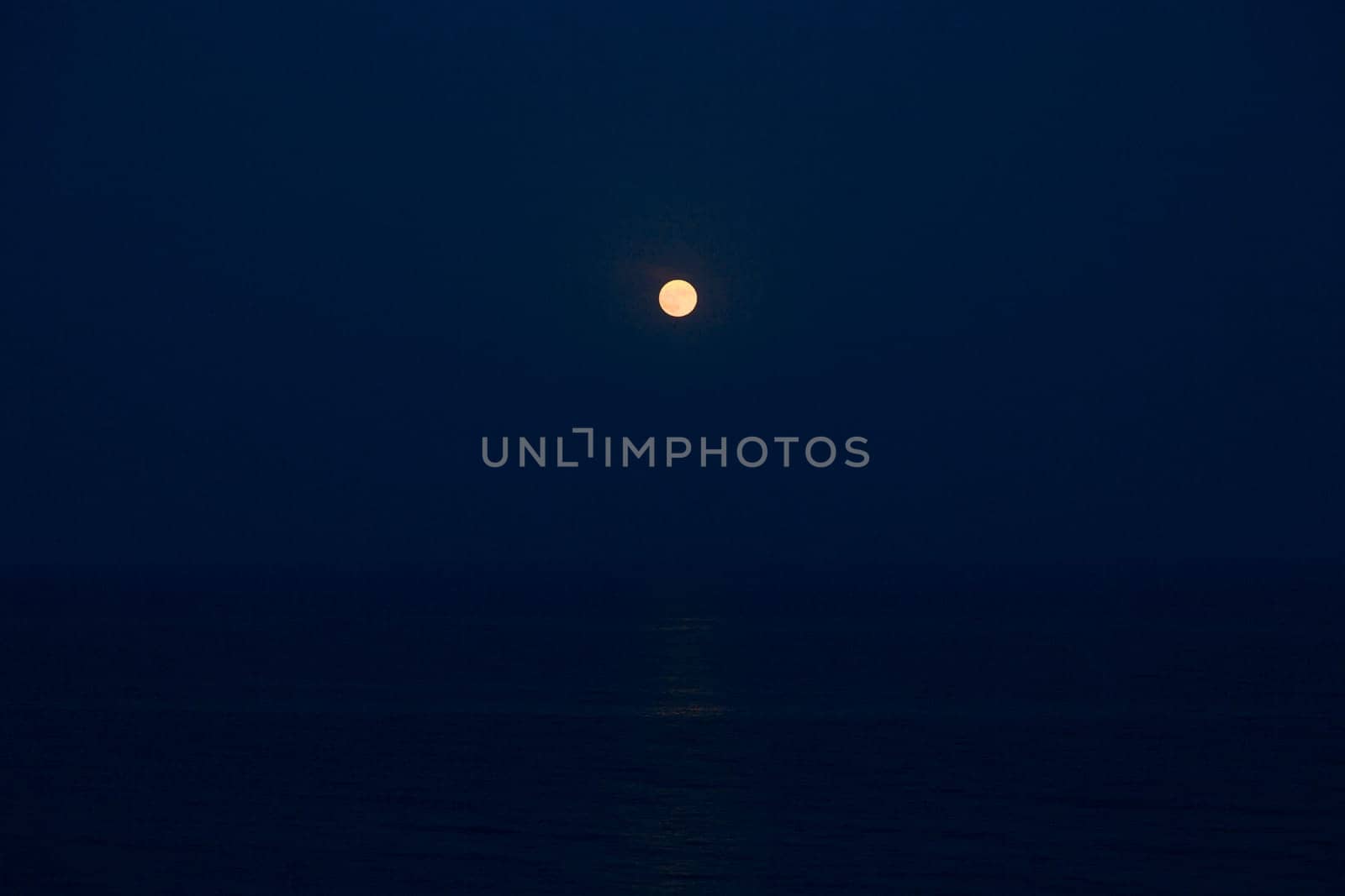 Full Red Moon Glows Brightly in the Blue Sky on a Evening Over the Sea.