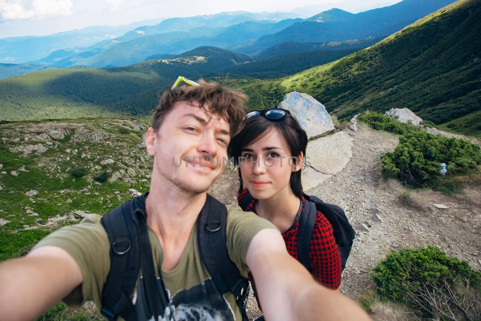 Aerial view of the Great Green Ridge. Guy and Girl Standing on a Big Hill against the Backdrop of a Huge Mountain Landscape.