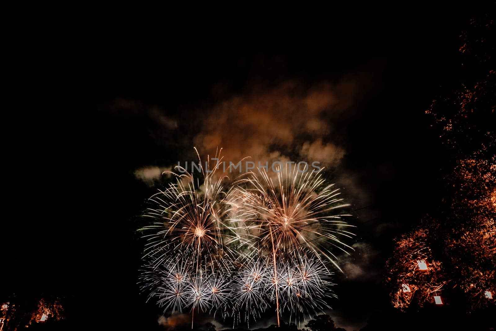 Group of people watching fireworks and using cellphones to record event. People capturing a fireworks shows with their mobile phone. Colorful fireworks celebration and the night sky background
