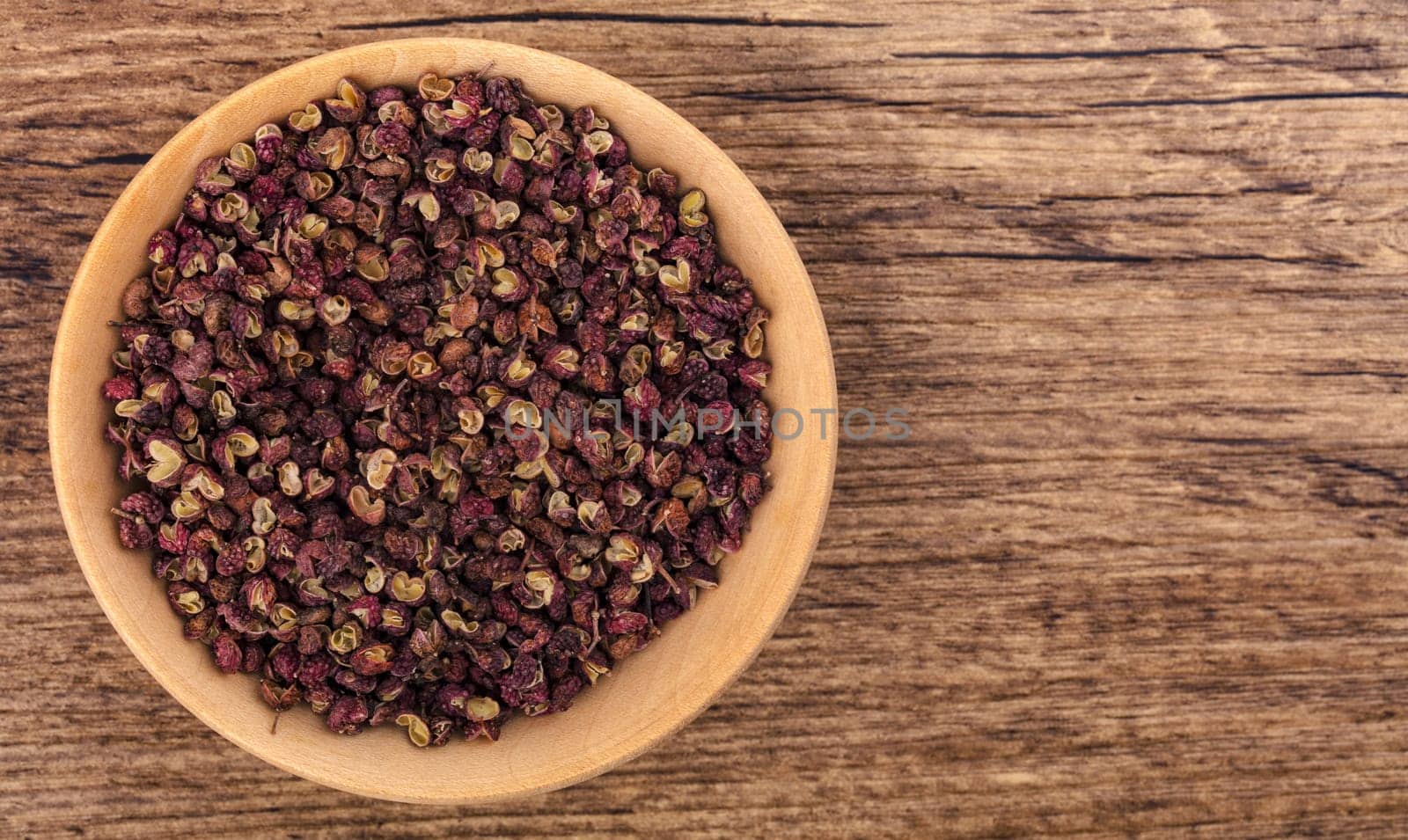 Szechuan pepper in a bowl over wooden background