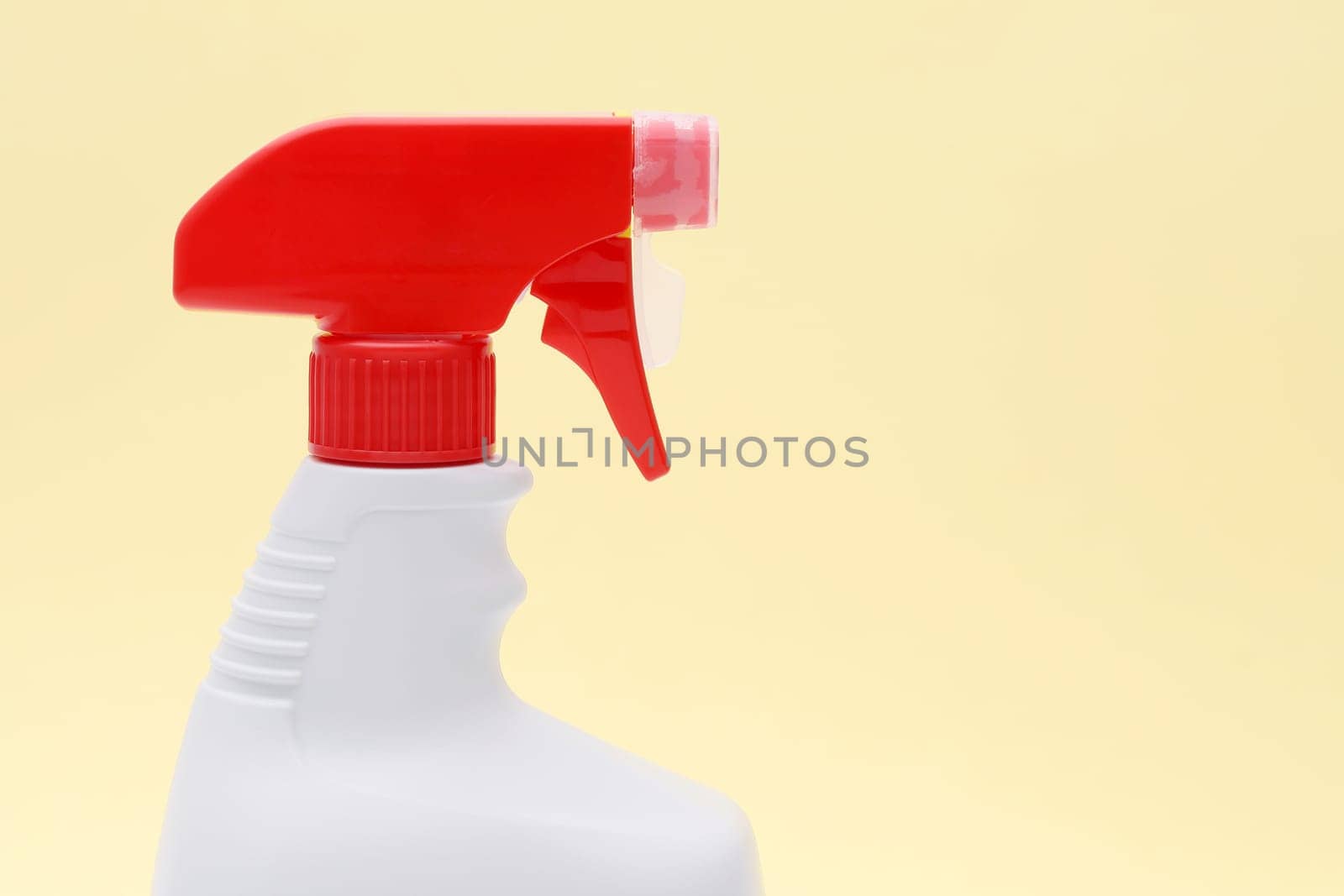 close up of white plastic bottle with spray and foam nozzle on yellow background