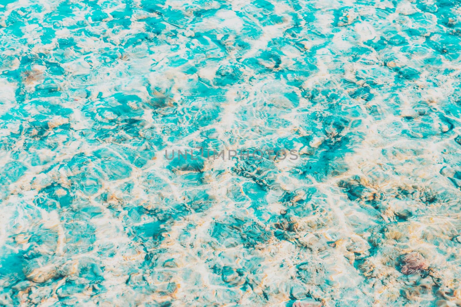 Vibrant blue white ripped water surface with clear transparent waves and nice sun sparkles over the reefs at Red sea or ocean. Conceptual abstract texture background. Travel or vacation summer concept