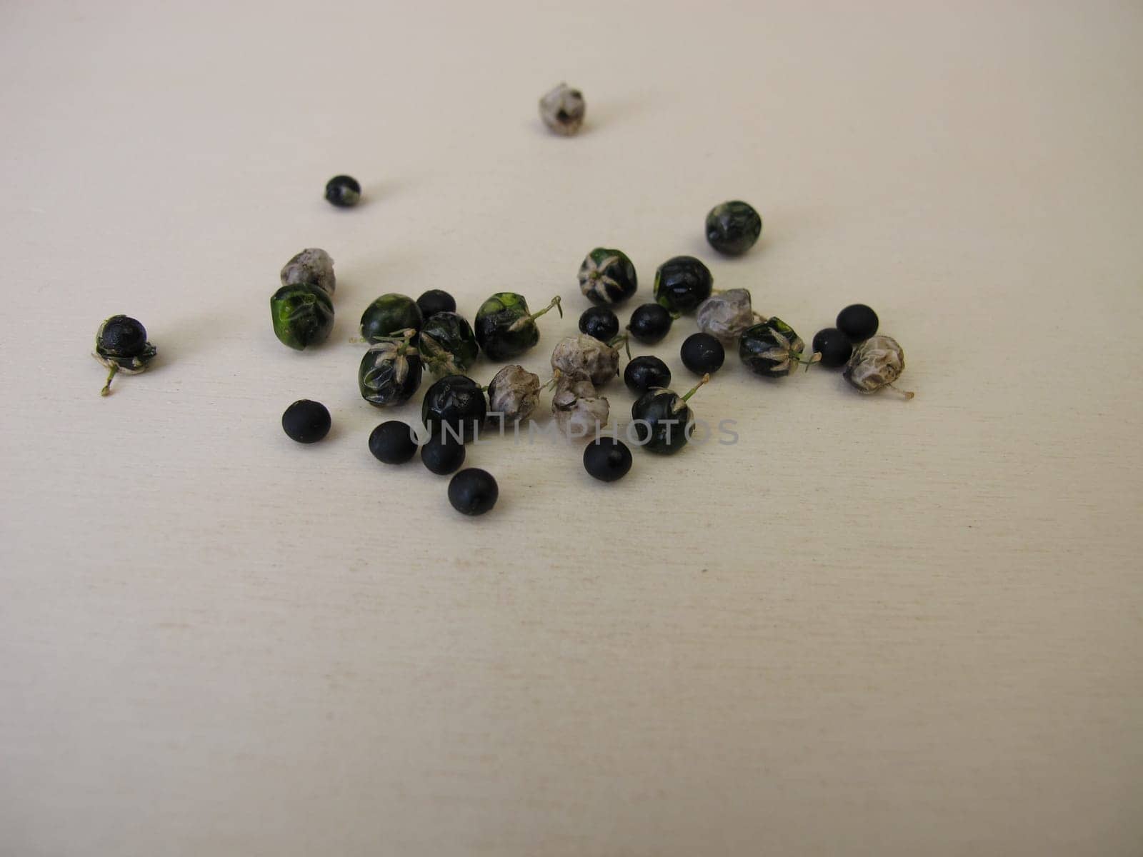 Asparagus seeds, fruits and black seed pods on a wooden board