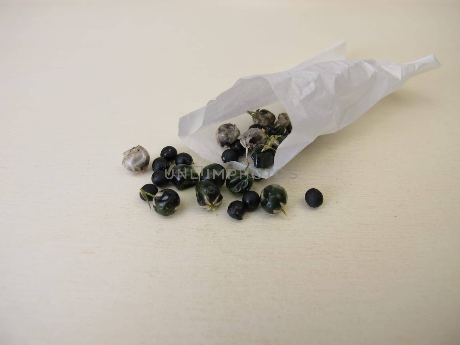 Asparagus seeds, fruits and black seed pods on a wooden board