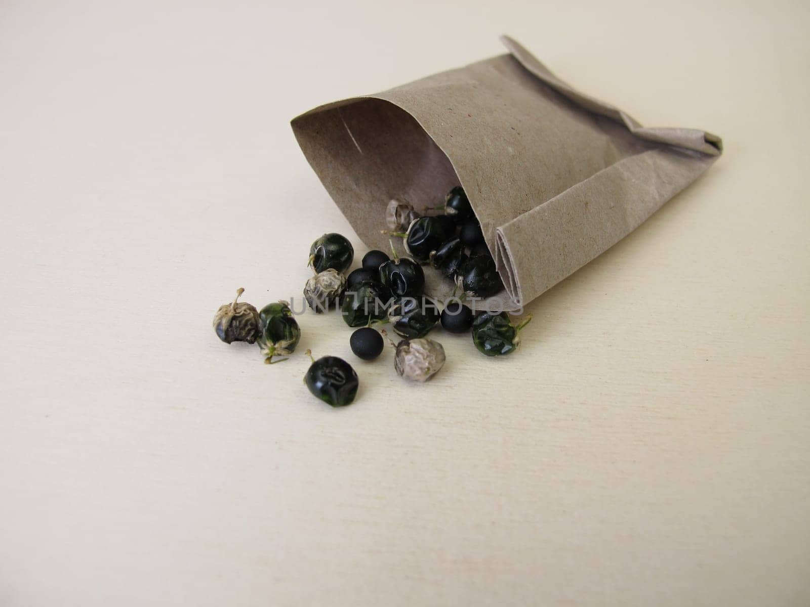 Asparagus seeds, fruits and black seed pods on a wooden board