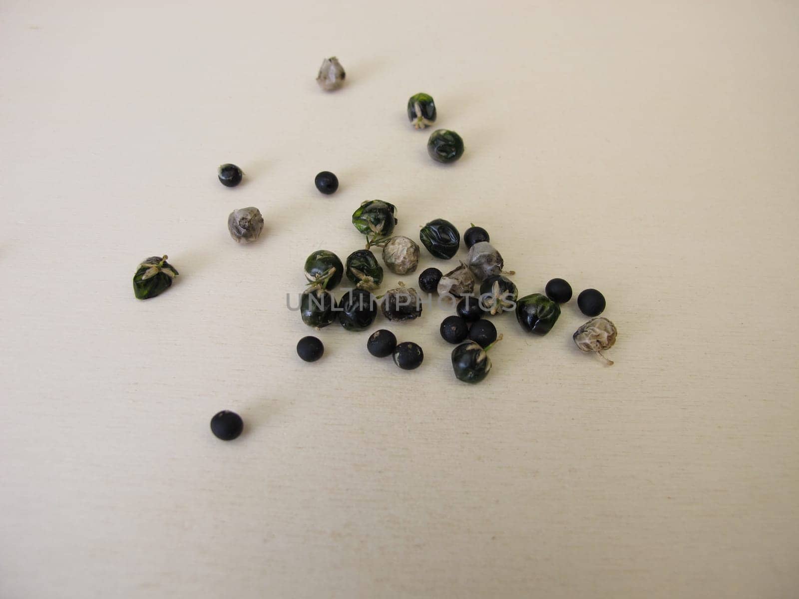 Asparagus seeds, fruits and black seed pods on a wooden board