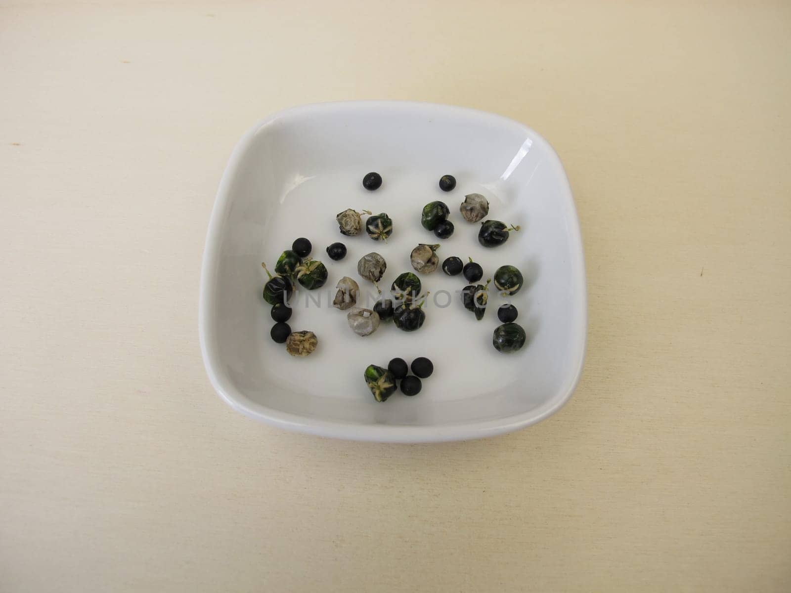Asparagus seeds, fruits and black seed pods on a wooden board